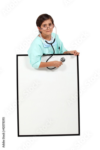 Foto: little boy dressed as a doctor using a stethoscope little boy dressed as a doctor using a stethoscope