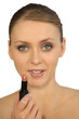 Woman putting on lipstick