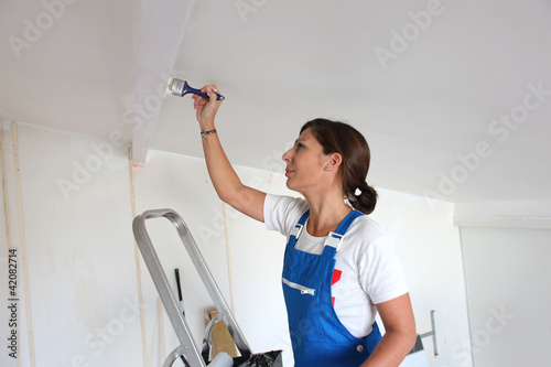 Foto: Woman painting a ceiling Woman painting a ceiling