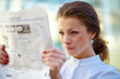 Young beautiful business woman reading newspaper