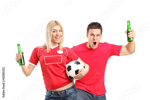 Foto: Male and female euphoric fans holding beer bottles and football Male and female euphoric fans holding beer bottles and football