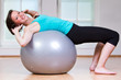 junge frau liegt mit dem Rücken auf gymnastikball