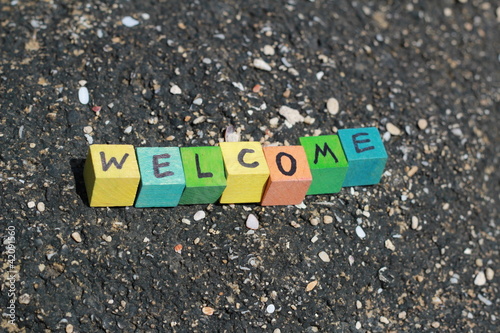 Photo: The word Welcome - written on wood cubes, at the beach The word Welcome - written on wood cubes, at the beach