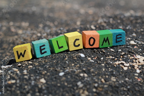 Photo: The word Welcome - written on wood cubes, at the beach The word Welcome - written on wood cubes, at the beach