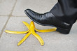 Businessman about to slip and fall on a banana skin