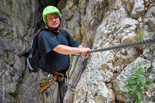 Foto: Young man climbing on via ferrata Young man climbing on via ferrata
