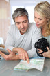 Mature couple planning vacation trip with map and laptop