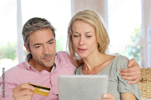 Foto: Couple sitting in sofa at home and doing online shopping Couple sitting in sofa at home and doing online shopping