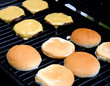 Cheeseburgers cooking on barbeque - buns toasting on side