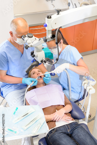 Photo: Dentist operating patient through microscope Dentist operating patient through microscope