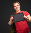 portrait of young man holding a digital tablet over black backgr