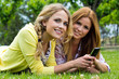 dos jóvenes amigas en el parque con un teléfono móvil
