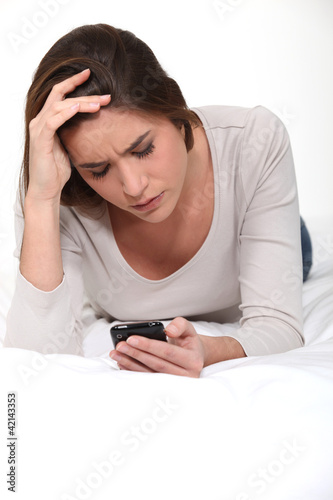 Photo: Frowning woman looking at her mobile phone Frowning woman looking at her mobile phone