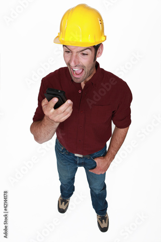 Photo: Angry builder shouting down mobile telephone Angry builder shouting down mobile telephone