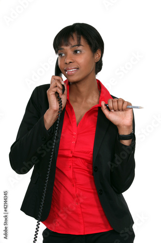 Photo: Office worker holding pen during phone call Office worker holding pen during phone call