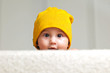 Photo: Cute Baby with a Beanie Hat behind a Sofa Cute Baby with a Beanie Hat behind a Sofa