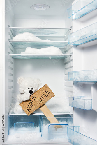 Photo: Polar bear in refrigerator with North Pole sign. Global warming Polar bear in refrigerator with North Pole sign. Global warming