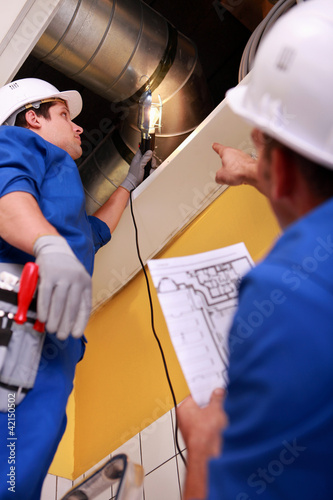 Photo: Two workers inspecting ventilation system Two workers inspecting ventilation system
