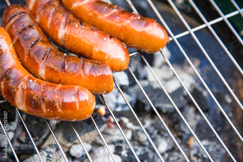 Photo: Tasty sausages burning on hot barbeque Tasty sausages burning on hot barbeque