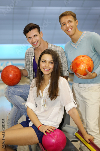 Photo: Two young men and girl with balls in bowling club; Two young men and girl with balls in bowling club;