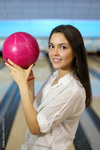 Foto: Young beatuiful woman holds pink ball in bowling club Young beatuiful woman holds pink ball in bowling club