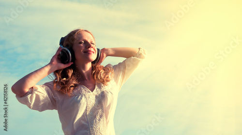 Photo: beautiful girl listening to music on headphones beautiful girl listening to music on headphones
