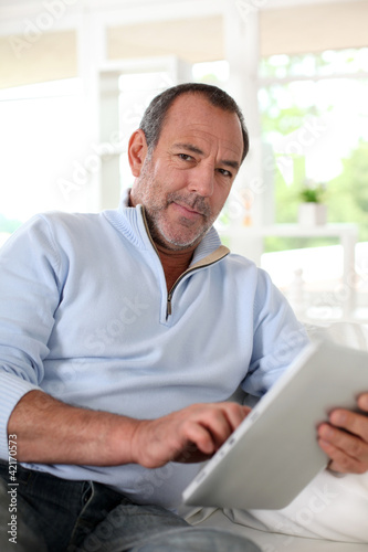 Foto: Senior man at home using electronic tablet Senior man at home using electronic tablet
