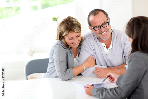 Photo: Senior couple signing financial contract Senior couple signing financial contract