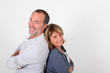 Senior couple standing back to back on white background