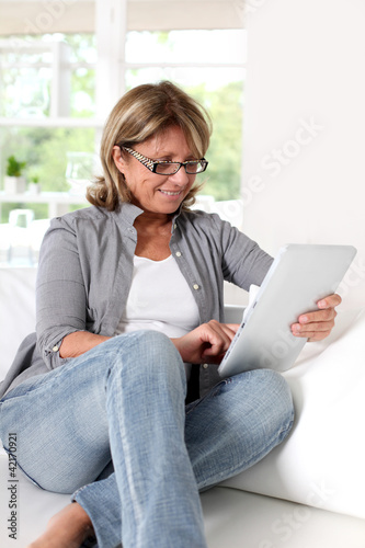 Foto: Smiling senior woman at home connected on internet Smiling senior woman at home connected on internet