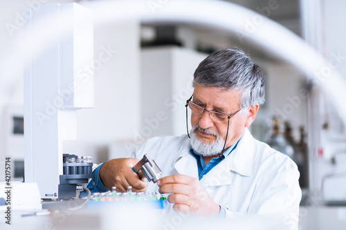 Photo: senior male researcher carrying out scientific research in a lab senior male researcher carrying out scientific research in a lab
