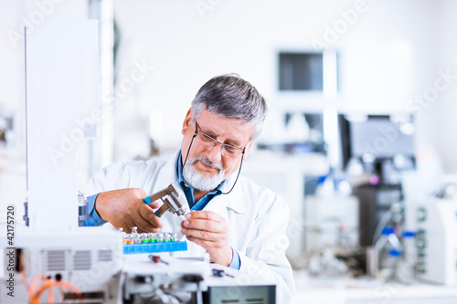 Photo: senior male researcher carrying out scientific research in a lab senior male researcher carrying out scientific research in a lab