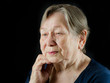 Sad old senior woman looking down and crying