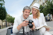 Happy tourists looking at pictures on camera screen