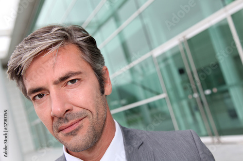 Foto: Portrait of businessman standing in front of modern building Portrait of businessman standing in front of modern building