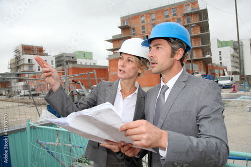 Photo: Construction engineers checking plan on building site Construction engineers checking plan on building site