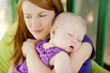 Eight months old baby sleeping in mothers hands