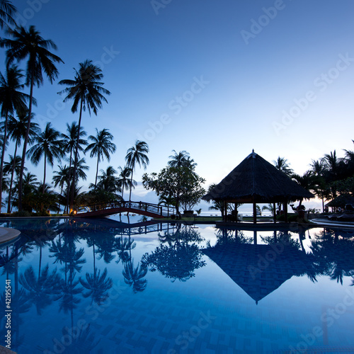 Foto: Amazing sunrise at swimming pool wit palms background Amazing sunrise at swimming pool wit palms background