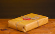 Parcel with sealing wax on wooden table on brown background