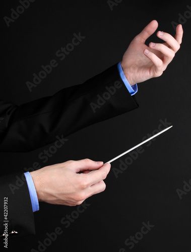 Photo: Music conductor hands with baton isolated on black Music conductor hands with baton isolated on black