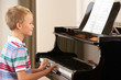 Young boy playing grand piano at home