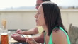 Woman talking and eating during lunch, man in background