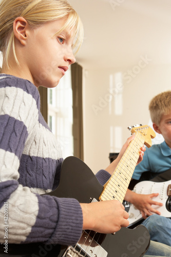 Photo: Boy and girl playing electric guitars at home Boy and girl playing electric guitars at home
