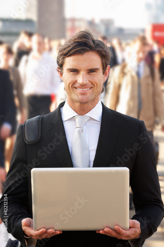 Photo: Male commuter in crowd using laptop Male commuter in crowd using laptop
