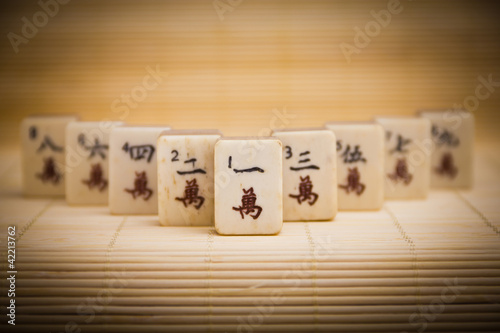 Photo: Old chinese game mahjongg on bamboo mat background Old chinese game mahjongg on bamboo mat background