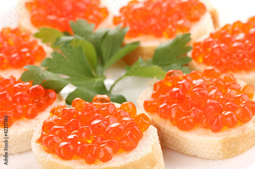 Photo: Red caviar on bread on white plate close-up Red caviar on bread on white plate close-up