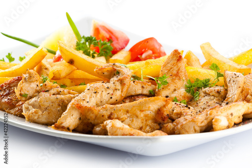 Photo: Grilled meat French fries and vegetables on white background Grilled meat French fries and vegetables on white background