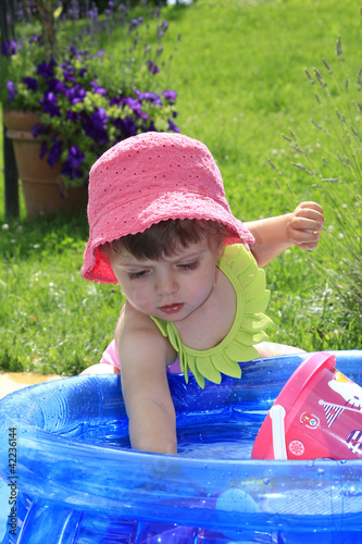 Foto: bambina in costume da bagno gioca con l'acqua bambina in costume da bagno gioca con l'acqua