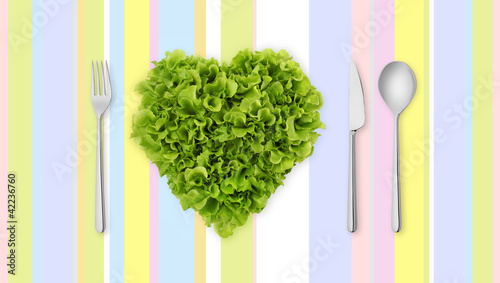 Photo: lettuce in the shape of heart on colored tablecloth with cutlery lettuce in the shape of heart on colored tablecloth with cutlery