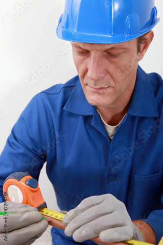Photo: Man measuring copper tube Man measuring copper tube